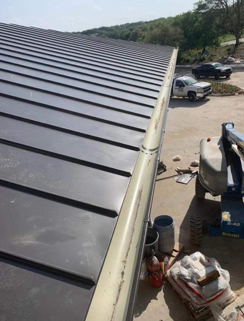Standing seam panel and gutter detail on a metal roofing jobsite in Warner Robins